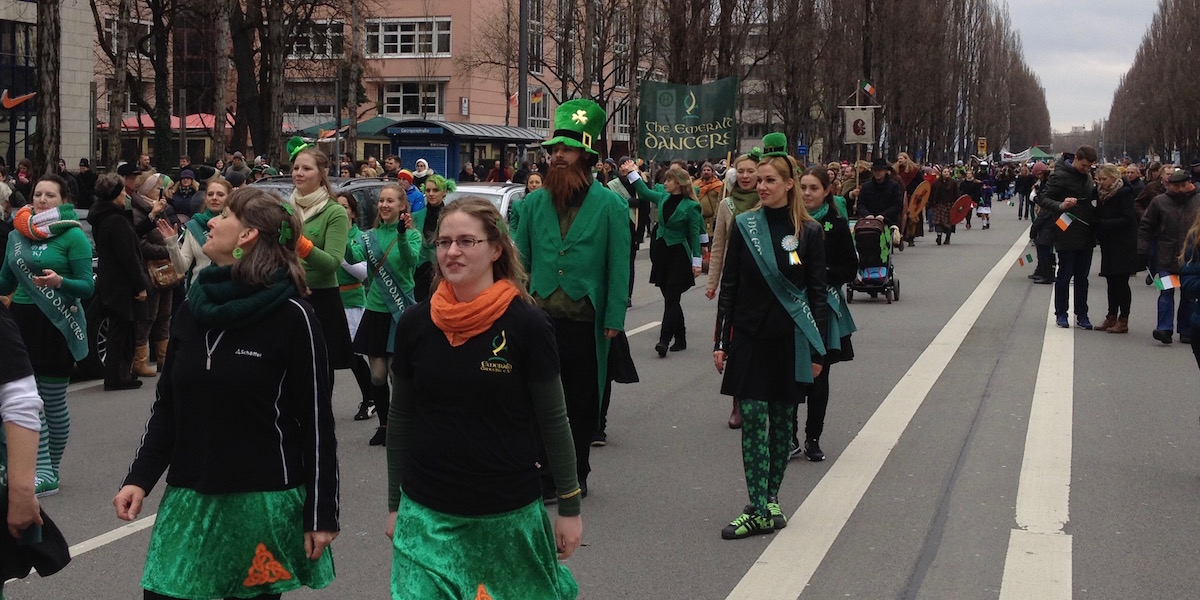 The Emerald Dancers in schwarz und grün gehen und tanzen die Leopoldstraße herunter.