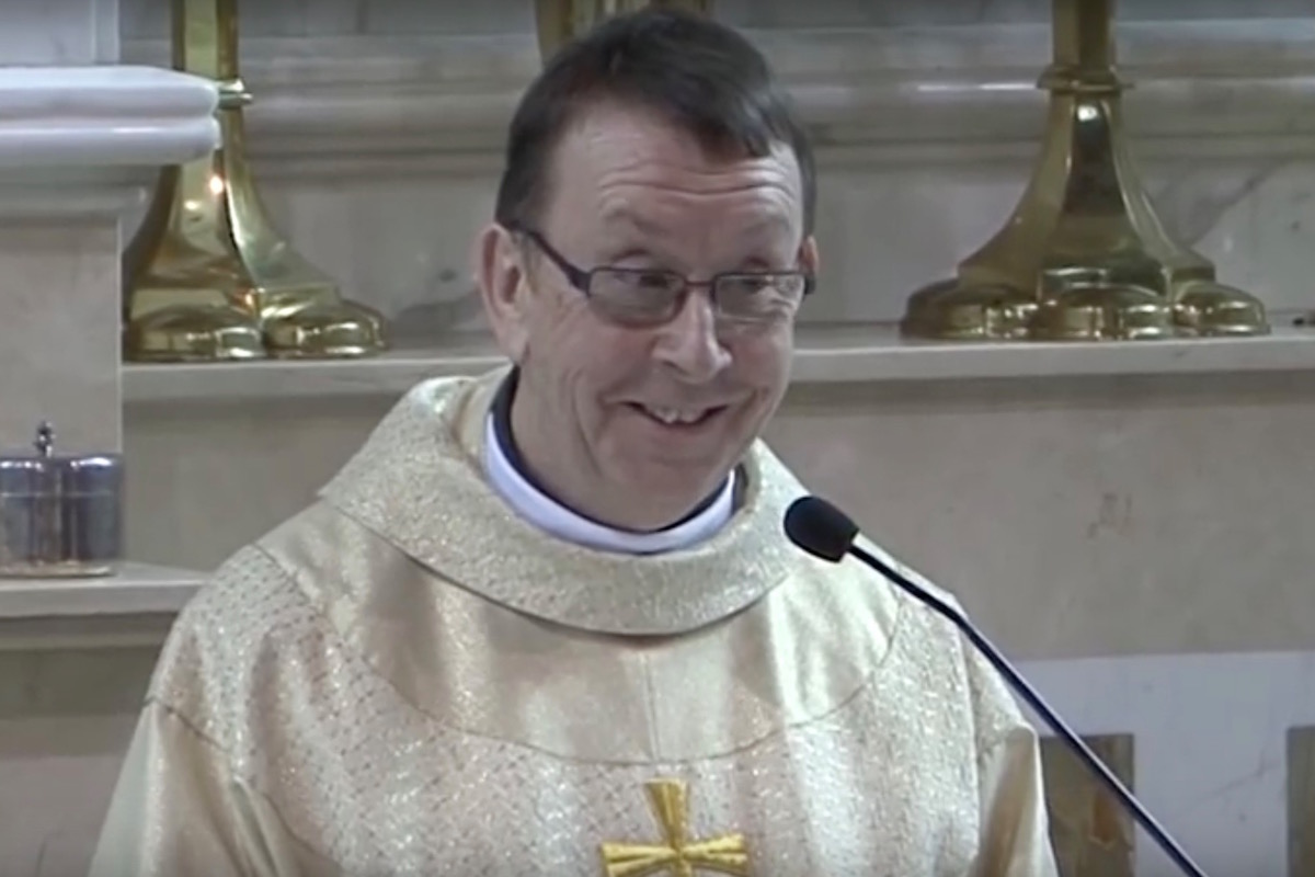 Father Ray Kelly sings Hallelujah and smiles.